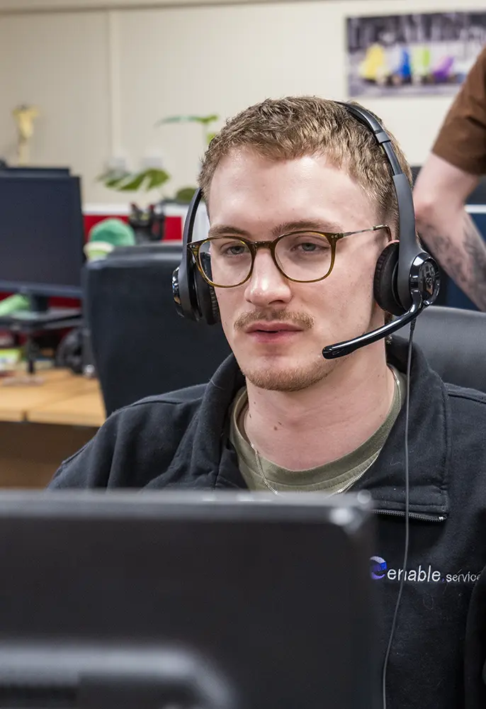 Man with headset on looking at computer screen intensely