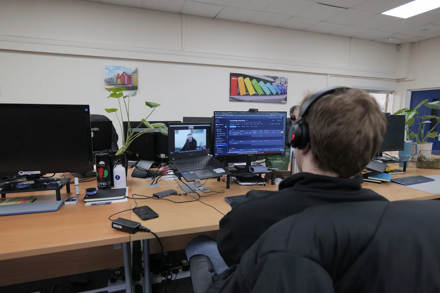 Back of man's head wearing headphones, on a video call on computer
