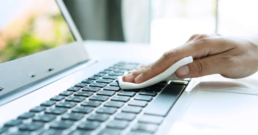 man hands wiping a laptop keyboard