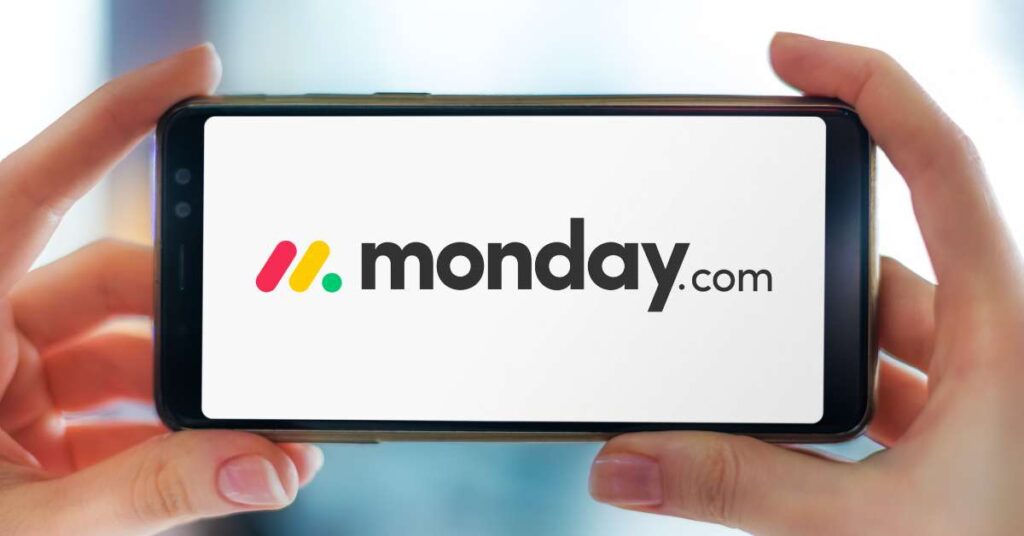 Hands holding a phone displaying monday.com logo