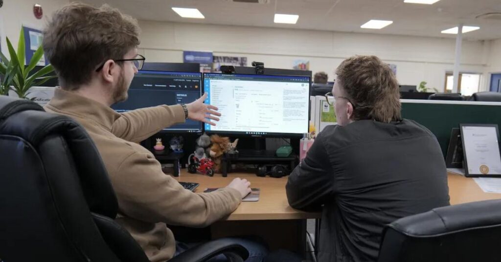 Man showing SugarCRM on computer to man
