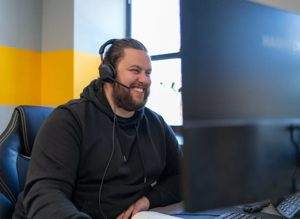 Man wearing headset smiling and using computer