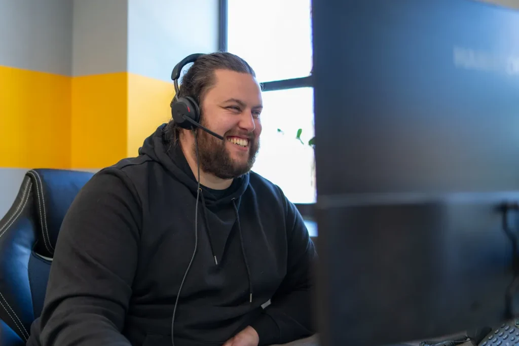 Man wearing headset smiling and using computer