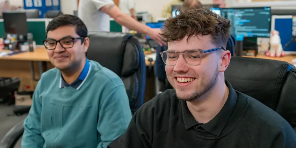 Two men in office smiling at computer
