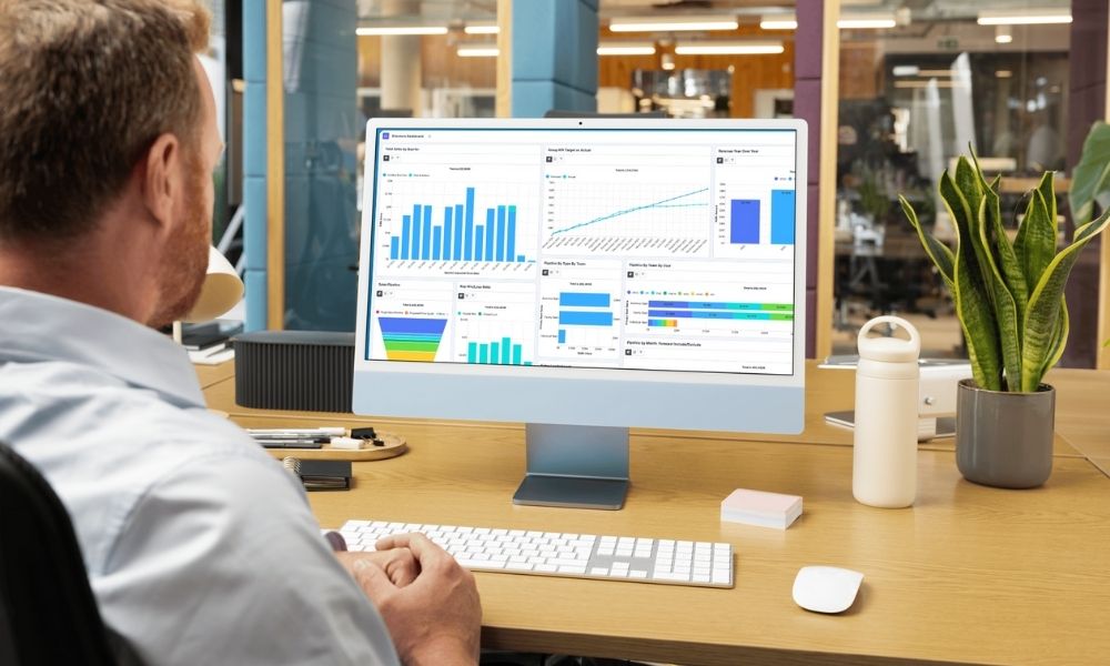 man at office desk looking at computer with sugarcrm dashboards on