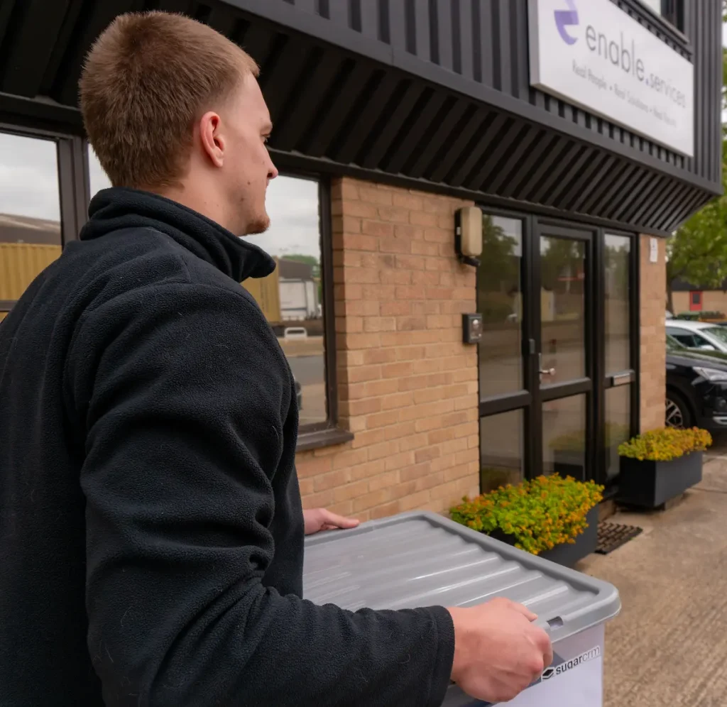 Man outside enable.services building holding box