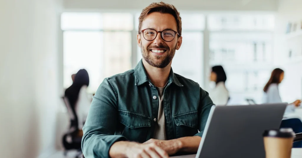 Businessman smiling sat in front of a laptop