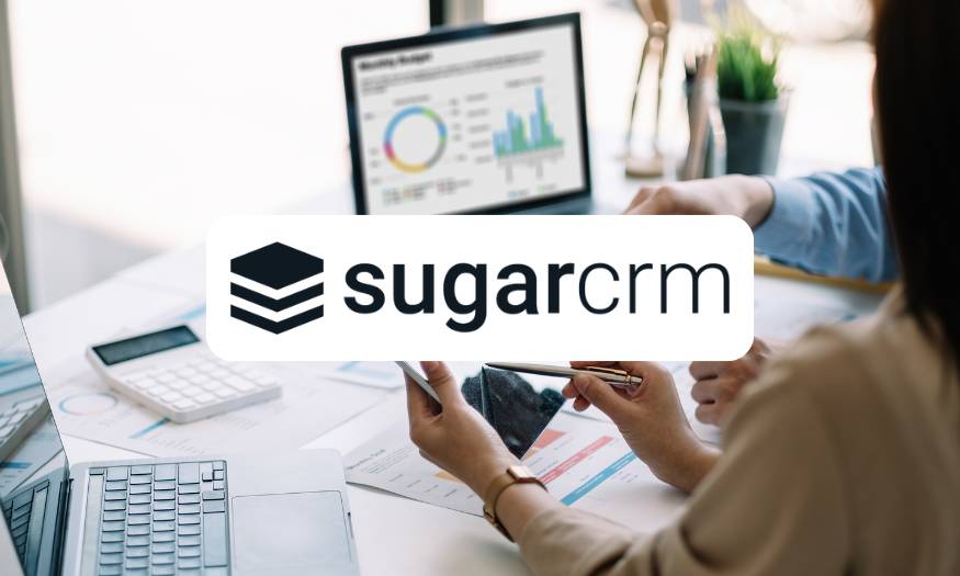 SugarCRM Logo over a photo of a desk with a laptop and paper highlighting charts