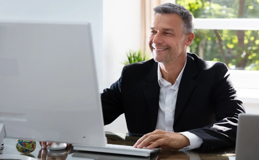 man looking at computer screen smiling