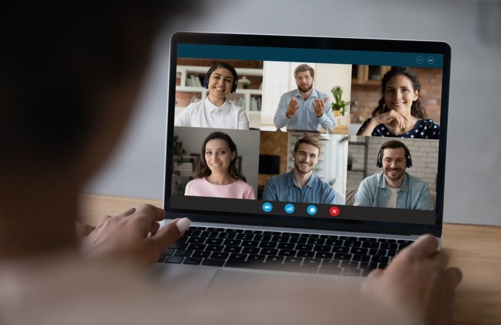 Laptop on desk with a video call on screen with 6 people