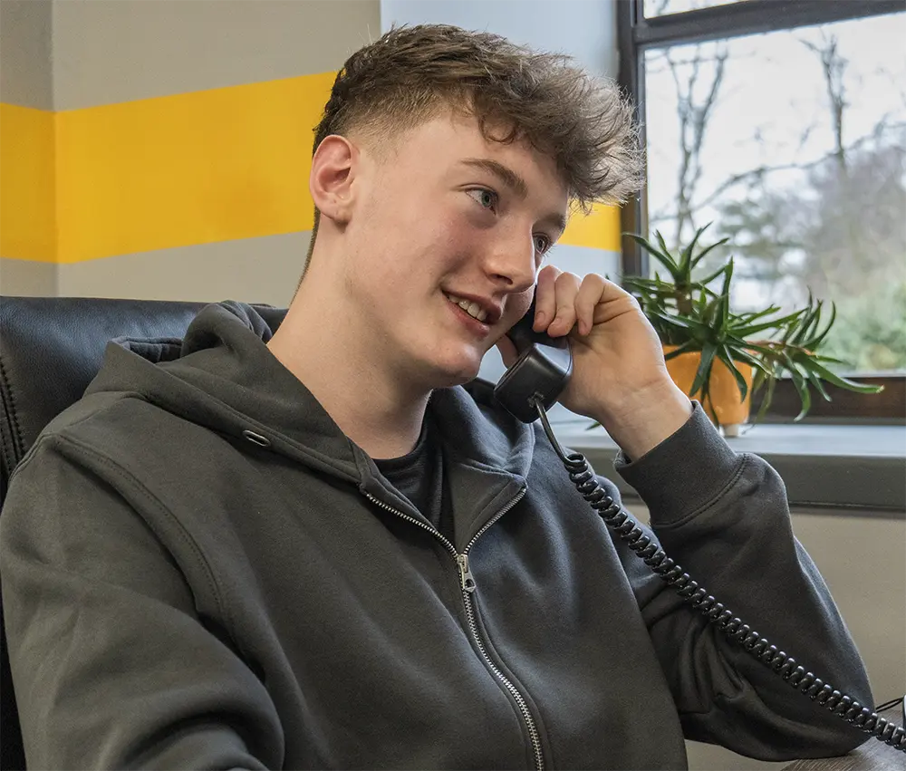 man holding a phone to his ear while sat at a desk