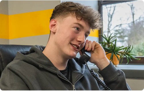 man holding a phone to his ear while sat at a desk