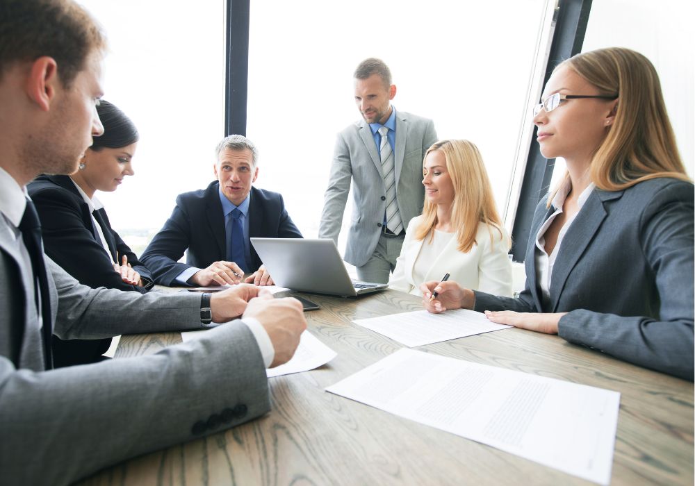 Group of men and women sitting around office table in a meeting